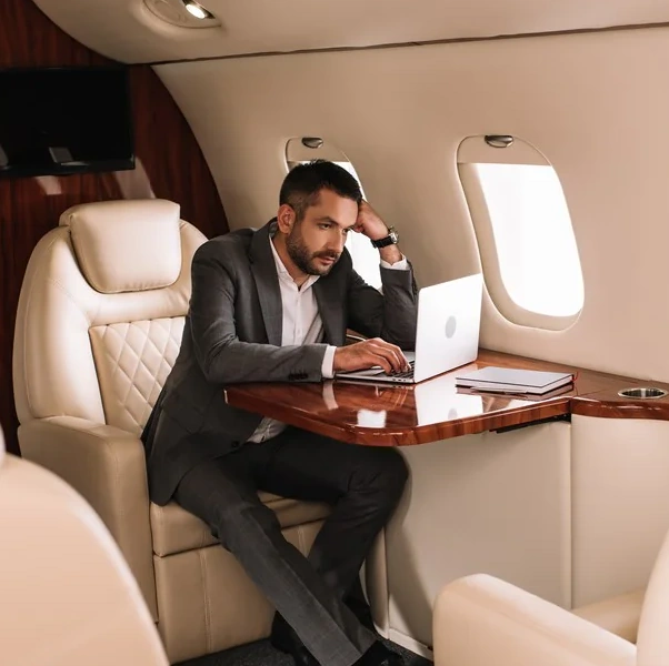 A businessman is sitting on a luxury jet seat preparing his meeting papers.