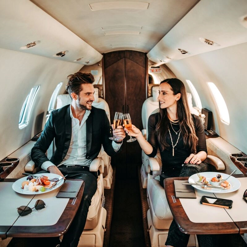 A couple enjoy the luxury service on the seats of a private jet.